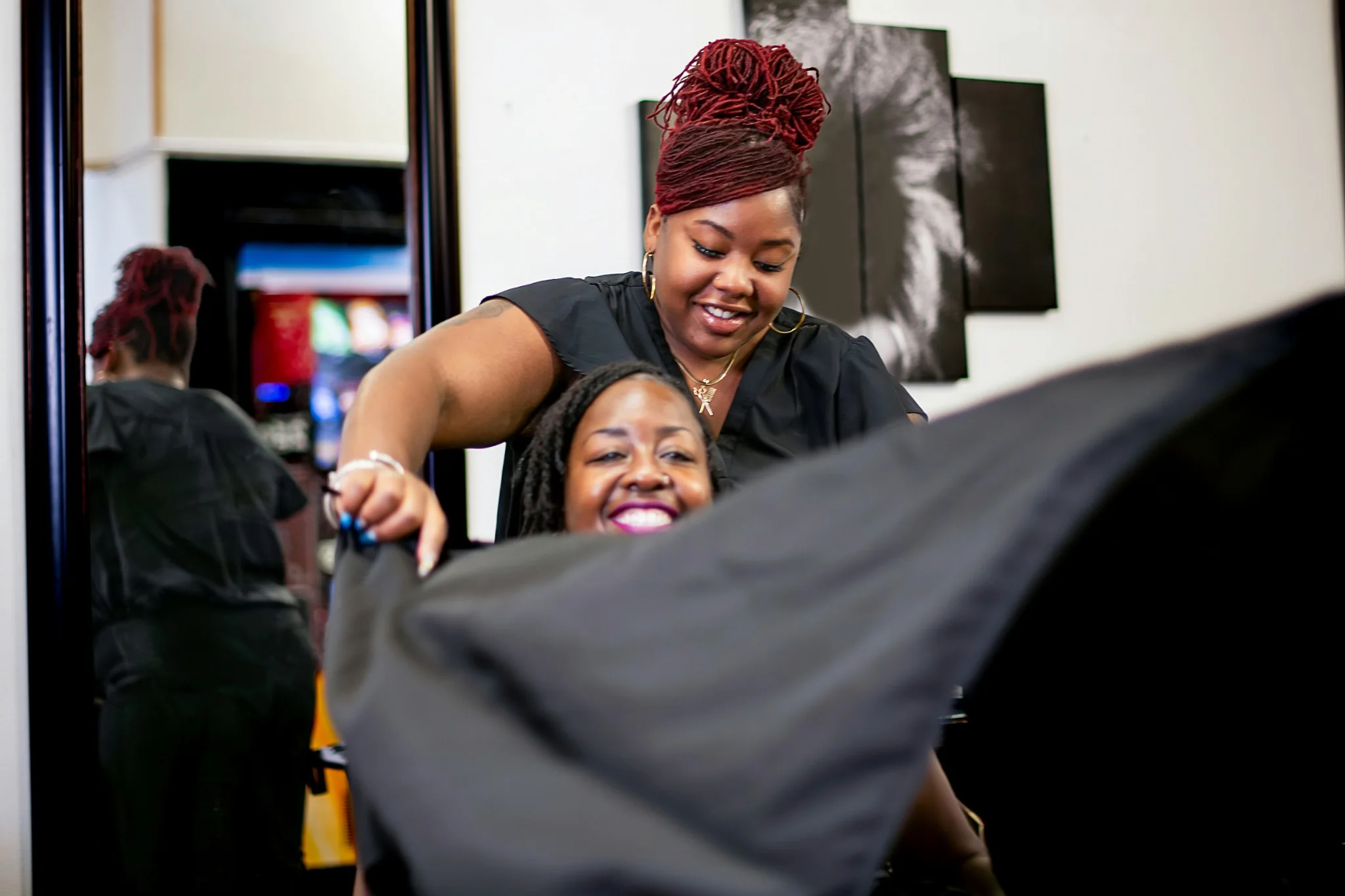 Hairstylist preparing a smiling client for a salon service