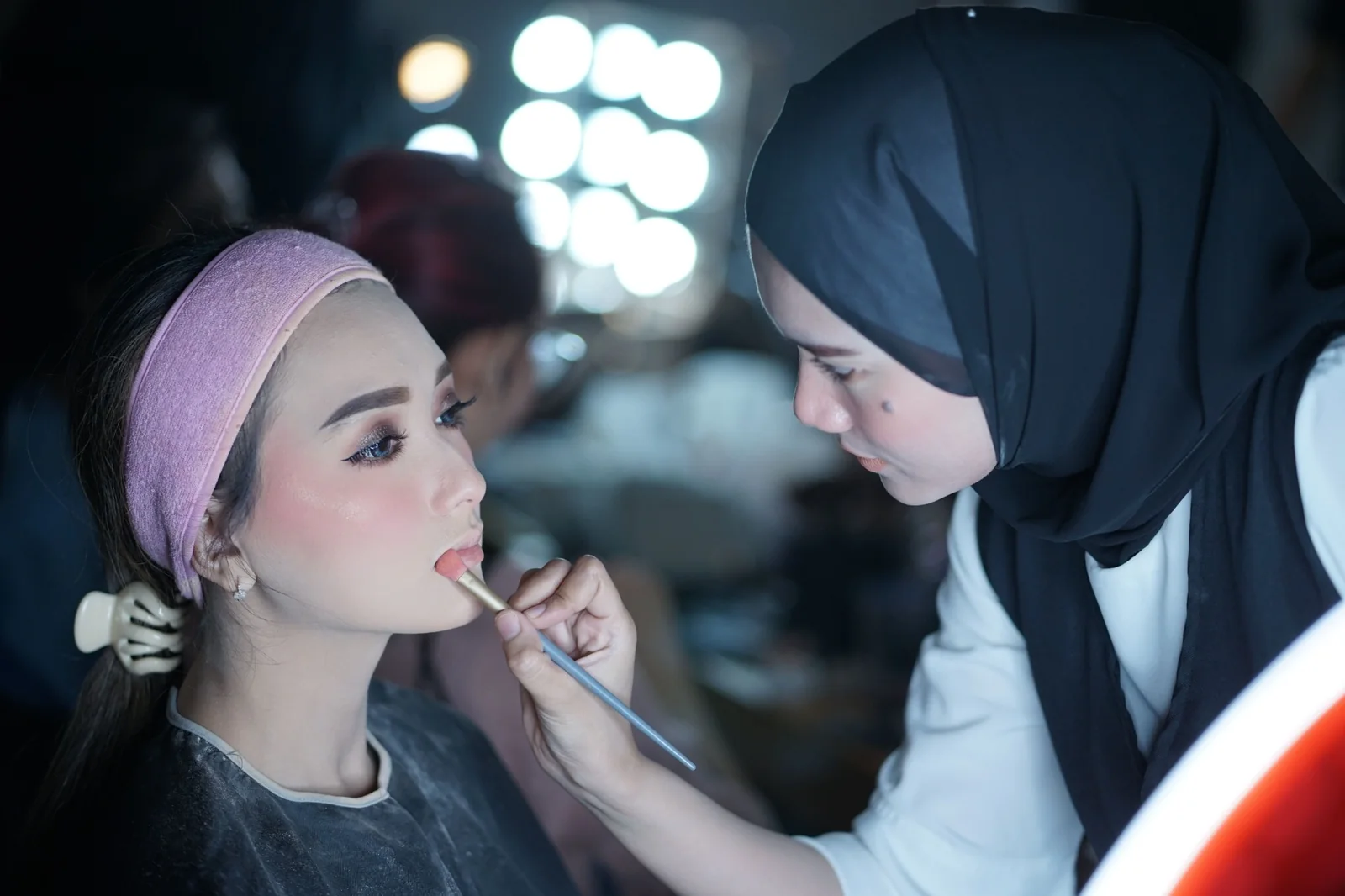 Makeup artist applying lip color to a client