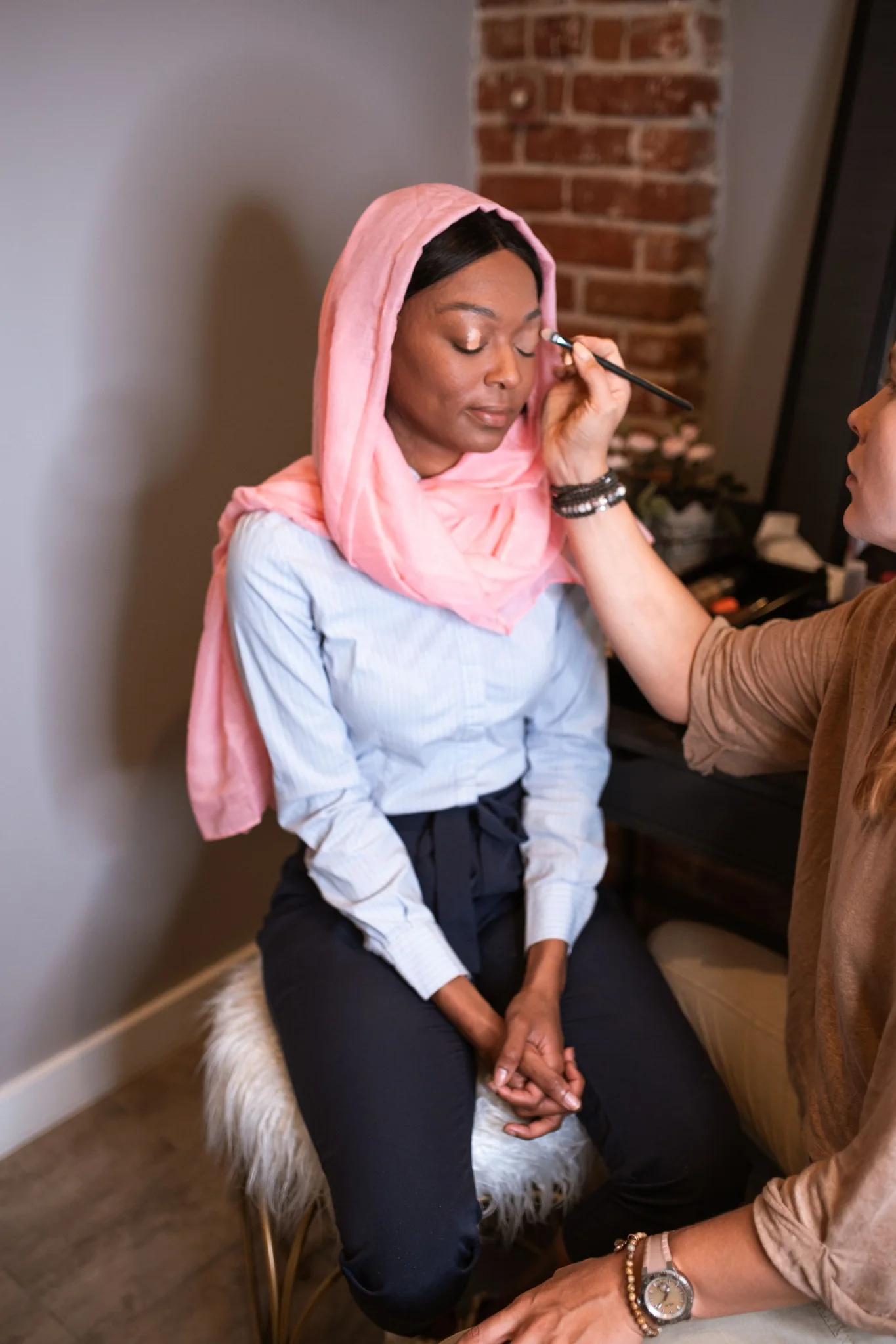Makeup artist applying eye makeup to a seated client