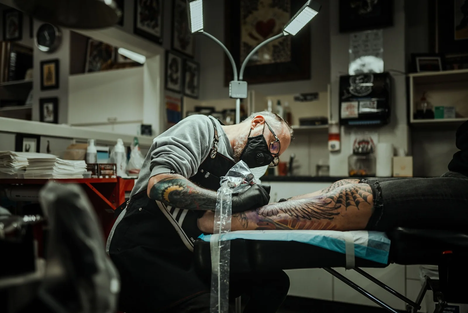 Tattoo artist working on a client's leg